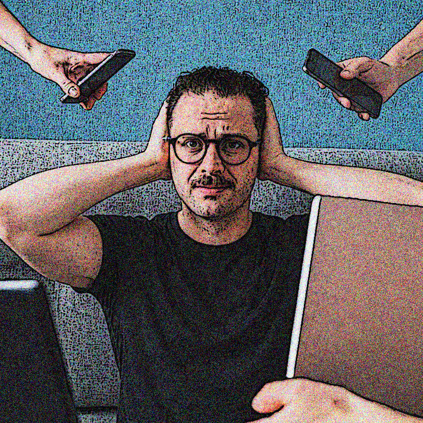 a man surrounded by various phones and laptops as he is overwhelmed by social media